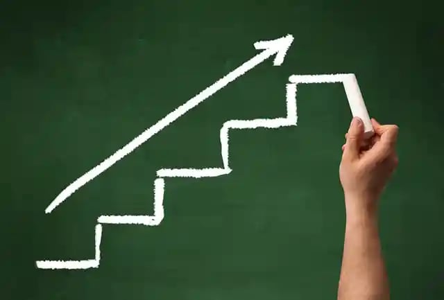 Stairs heading upwards with an arrow drawn by hand on a green chalkboard